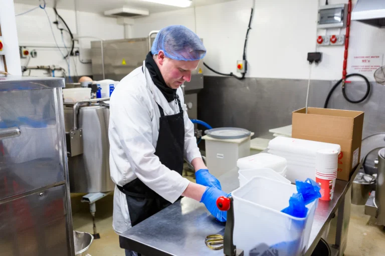 Worker preparing food in commercial kitchen.