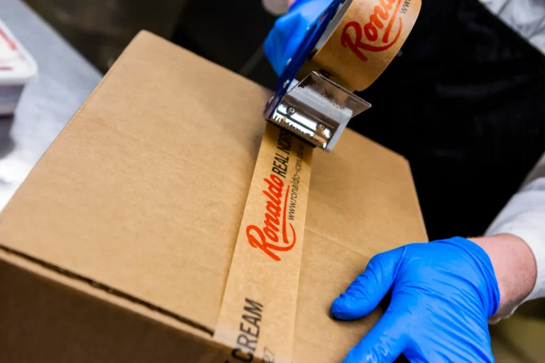 Person sealing box with branded tape.