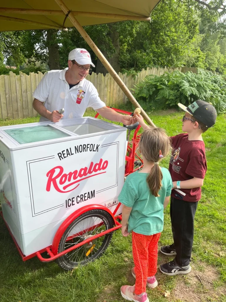 Vendor serving ice cream to children outdoors.